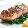 Grilled salmon on a bed of spinach with a lemon wedge