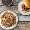 Pulled pork on a plate and bun with a side of BBQ sauce