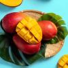 Diced fresh mango with green tropical leaves on a blue table