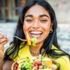 Happy woman laughing and eating a healthy peach and lettuce salad