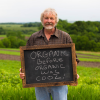 Pete Gengler, Owner of Sno Pac Foods, holding a chalkboard sign that says 'Organic before organic was cool'