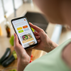 Woman using a dieting app on her smartphone while preparing food