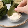 Dipping roasted artichoke petals in creamy sauce or dip
