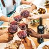 A group of friends clink glasses of rich red wine at a backyard patio party