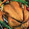Roasted turkey in a pan with root vegetables and rosemary sprigs
